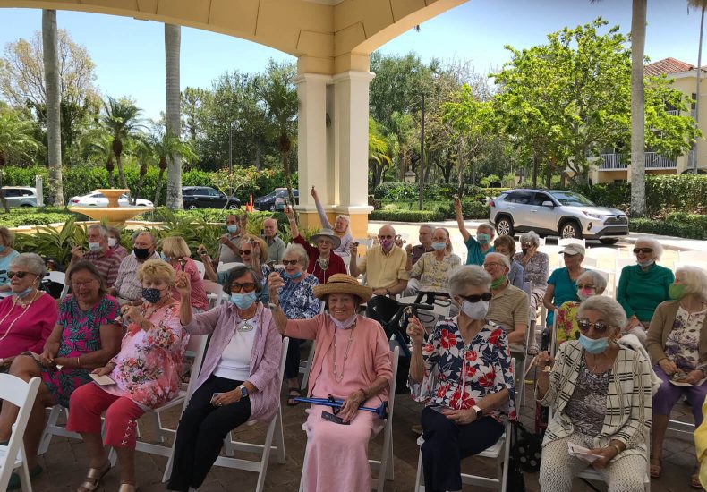 Senior citizens at a Cape Coral, Florida senior living community, happily waving to the camera.