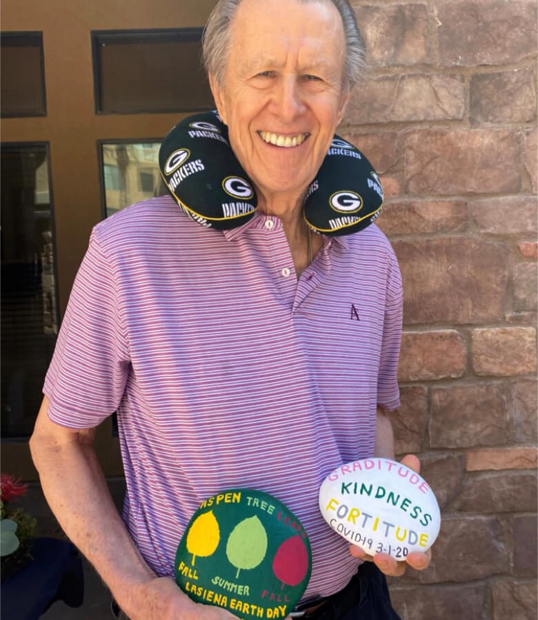 An elderly man holding 2 painted rocks, showcasing his passion for earth day
