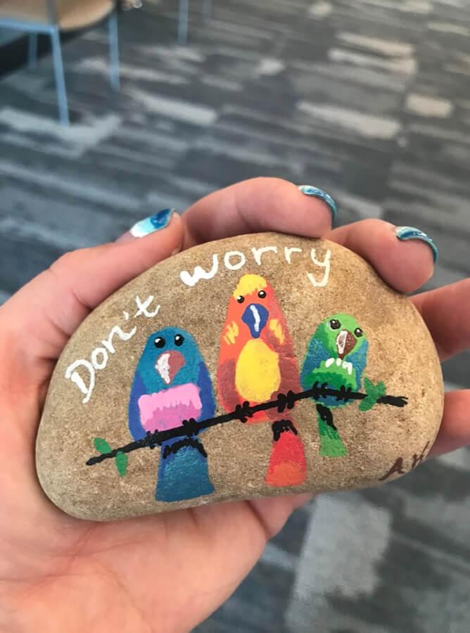 A hand-painted rock featuring two birds perched on it.