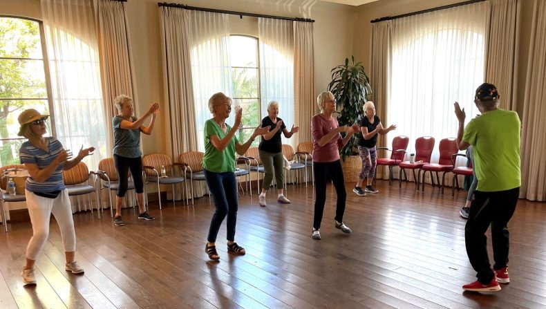 A lively dance performance by a group of people in a room, showcasing their synchronized moves and vibrant energy.