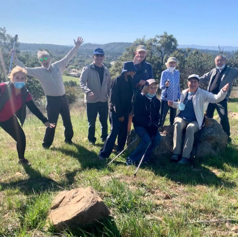 A group of people smiling and posing for a photo on a beautiful hillside landscape