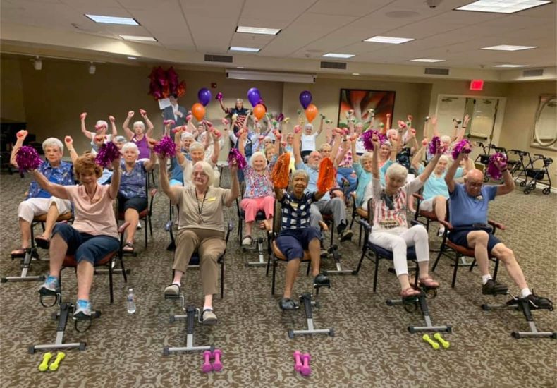 A group of elderly individuals sitting on exercise bikes, engaging in a fitness activity together.