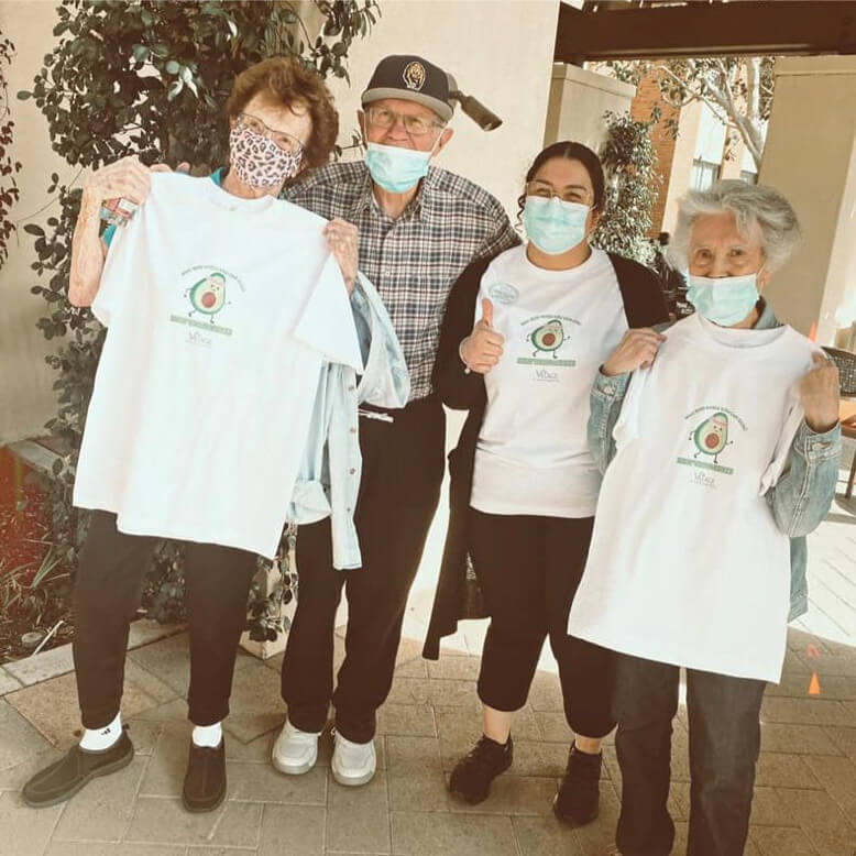 Three people wearing face masks and holding t-shirts.