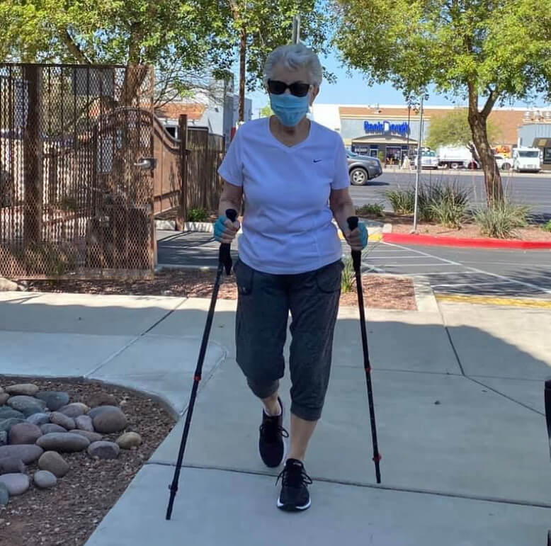 An elderly woman skiing while wearing a face mask for protection against airborne particles.