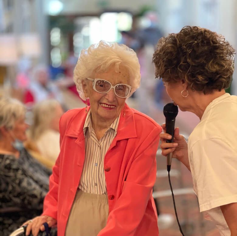 An older woman engages in conversation with a woman in a wheelchair, displaying empathy and understanding.