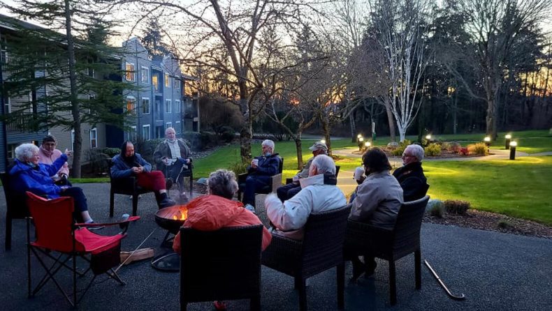 A group of individuals gathered around a fire pit in a park, enjoying the warmth and camaraderie.