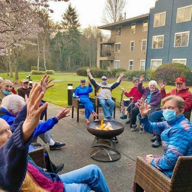 A gathering of individuals seated around a fire pit, enjoying each other's company and the warmth of the fire.