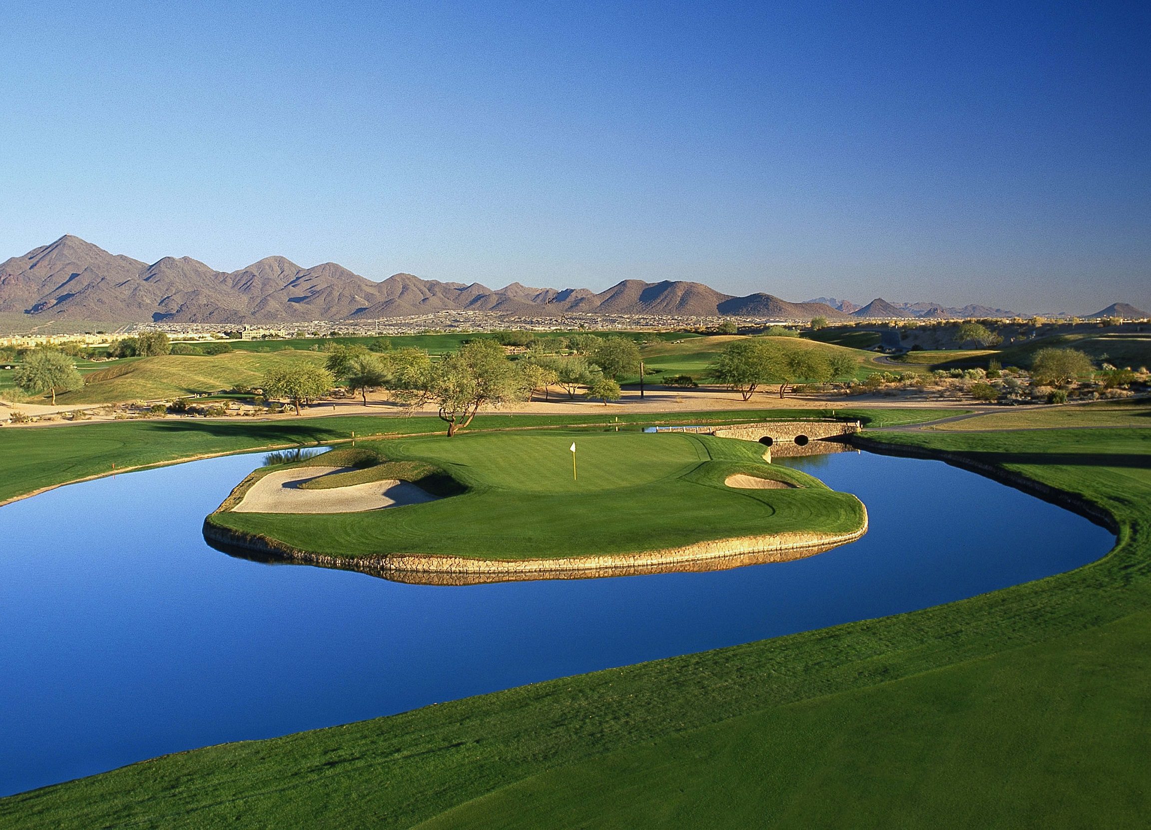 arial view of lush golf course in desert, with mountain in background