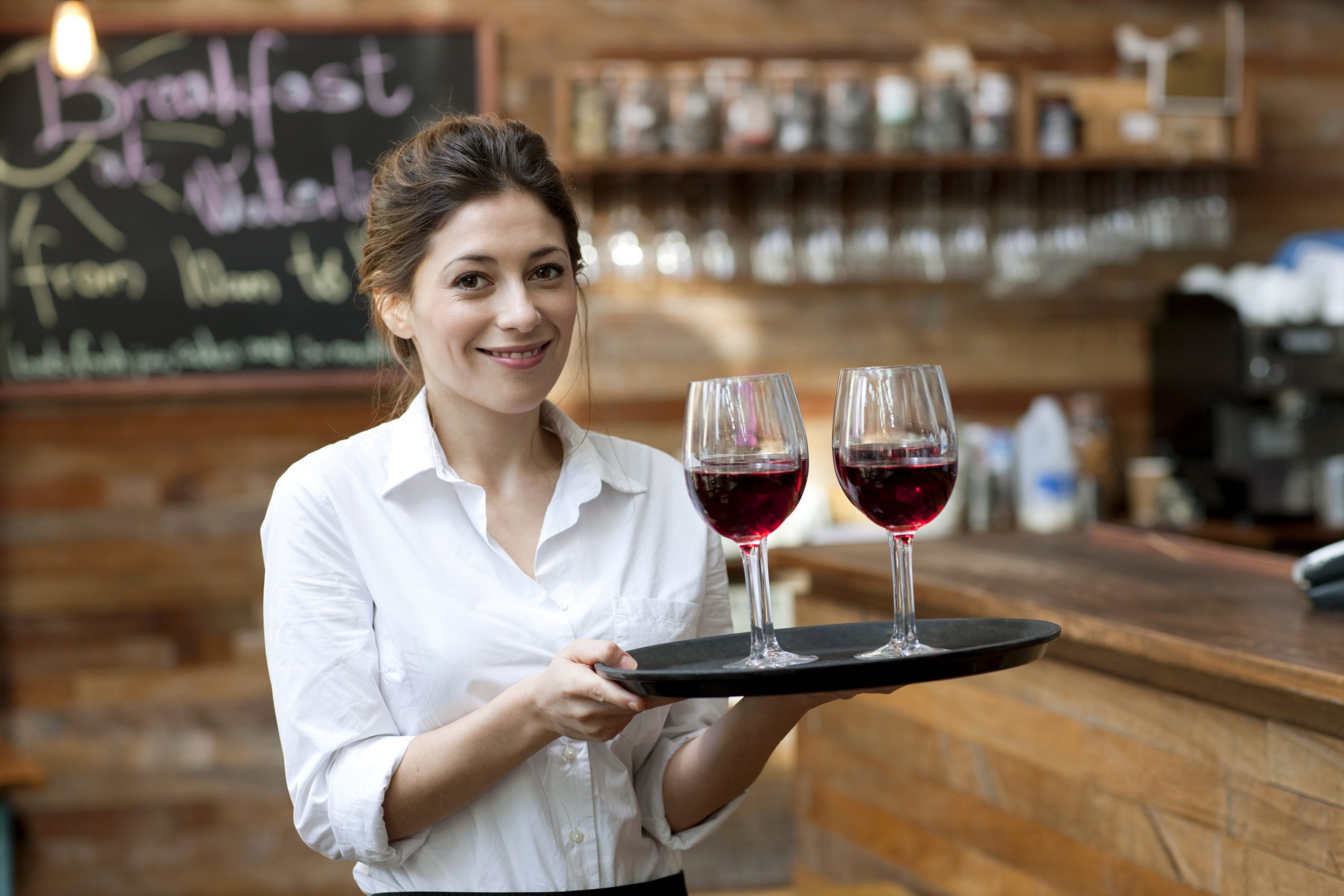 A woman gracefully holds two glasses of red wine, showcasing elegance and sophistication.