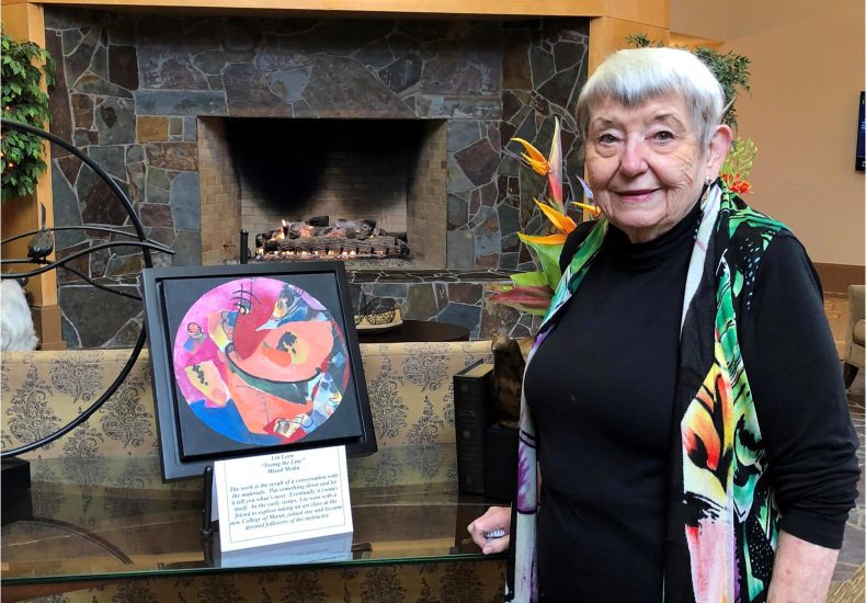 An elderly woman admires a painting, showcasing her appreciation for art and culture.