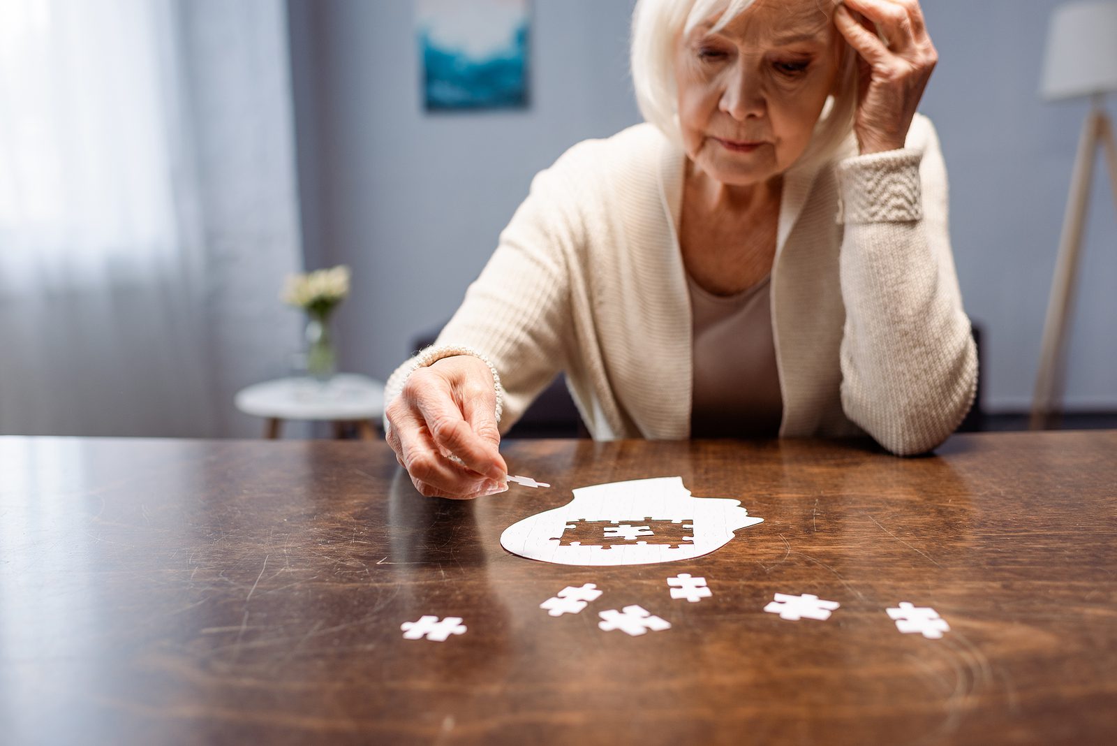 Senior Woman Combining Jigsaw Puzzle For Dementia Rehabilitation Older adult woman doing a puzzle