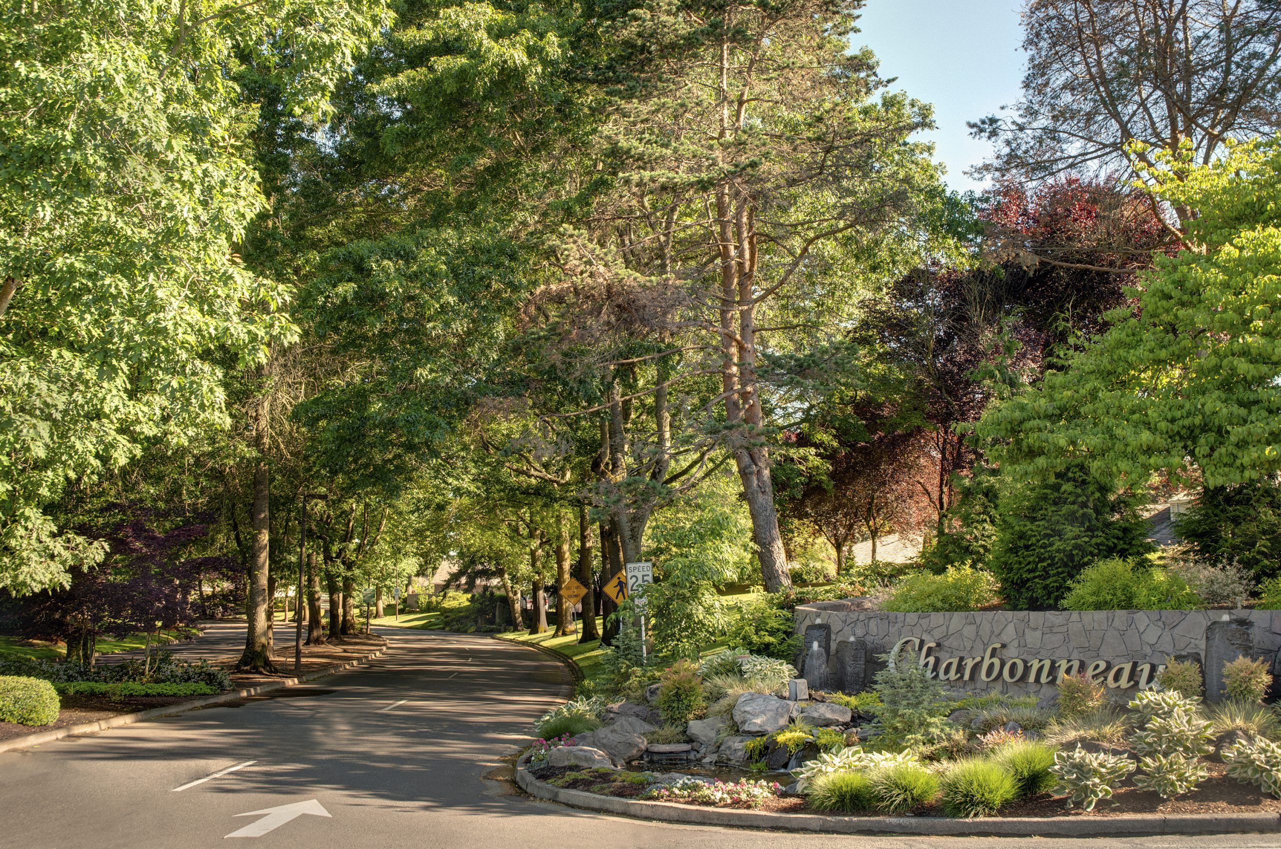 A serene street lined with trees and a signpost that says charbonneau