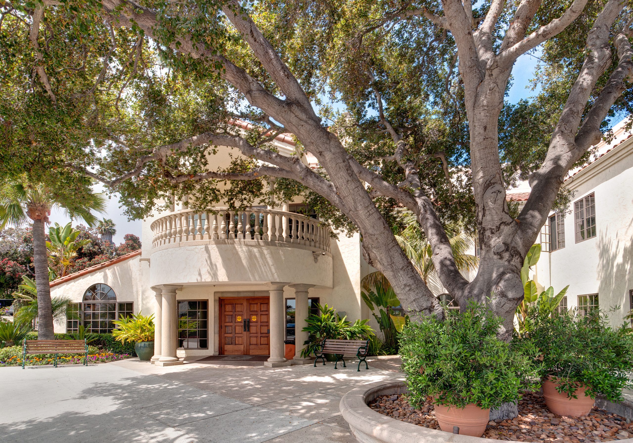 Entrance to courtyard, featuring lush greenery and a grand archway.