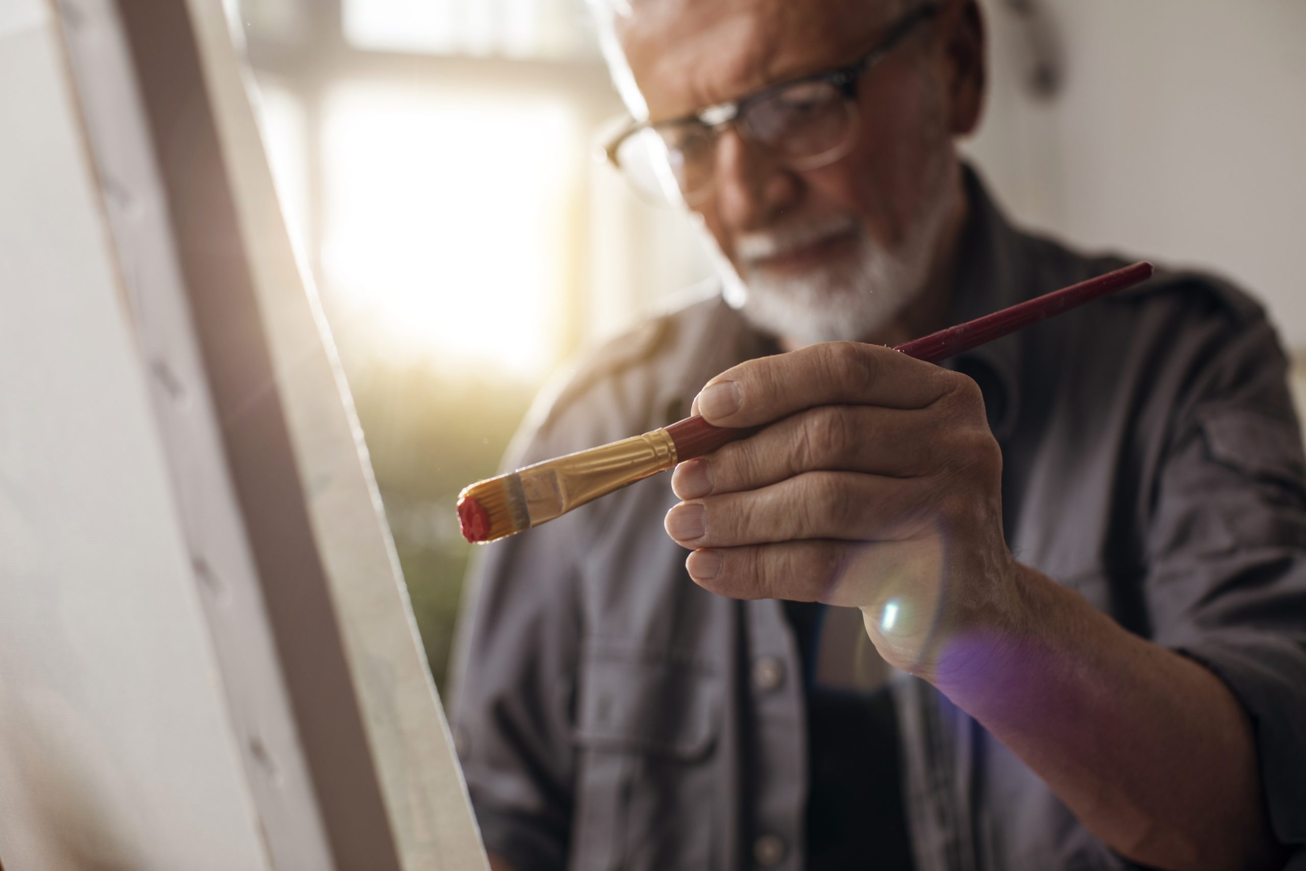 elderly man painting with a canvas