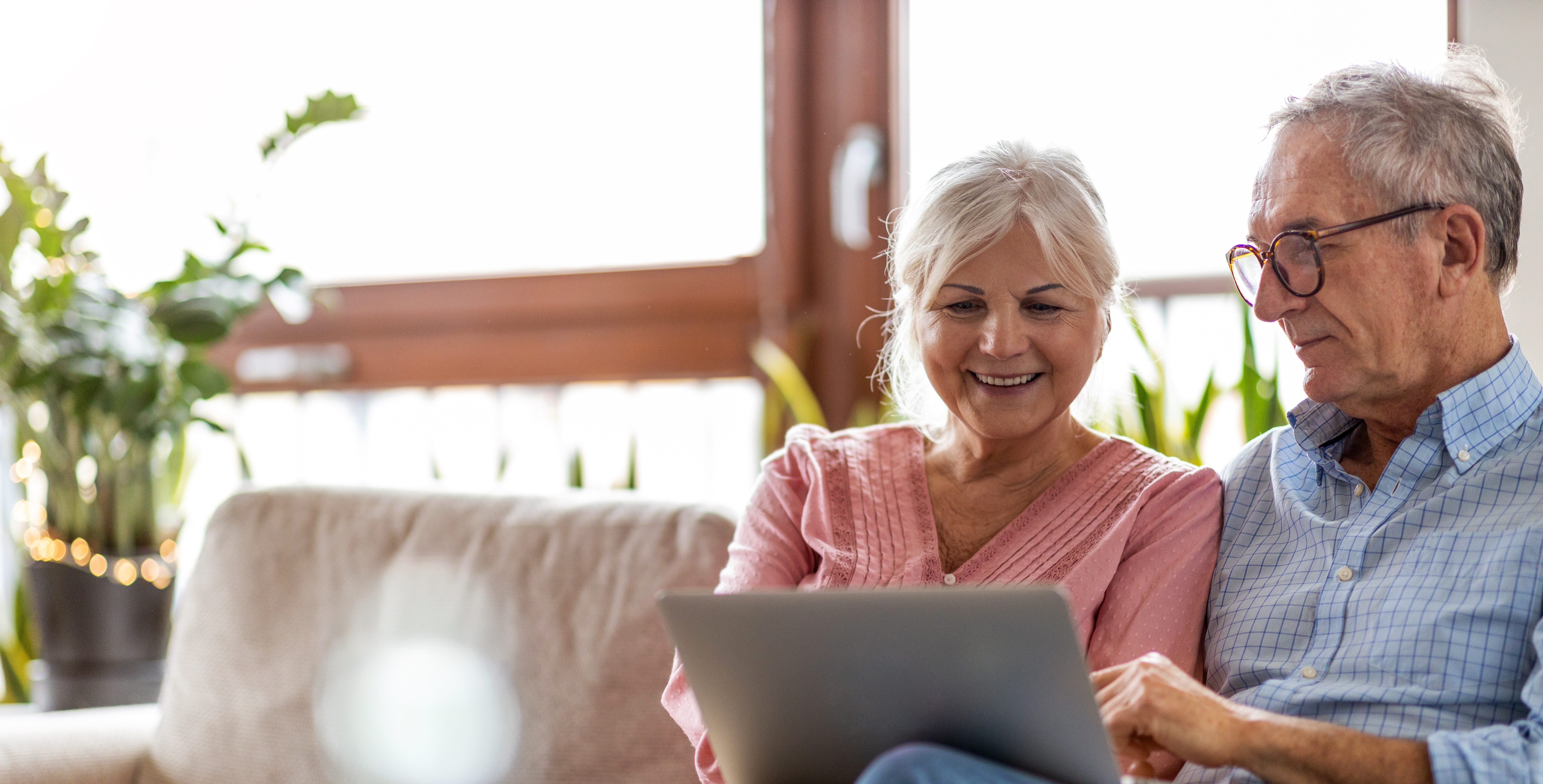 seniors looking at laptop on the couch woman smiling