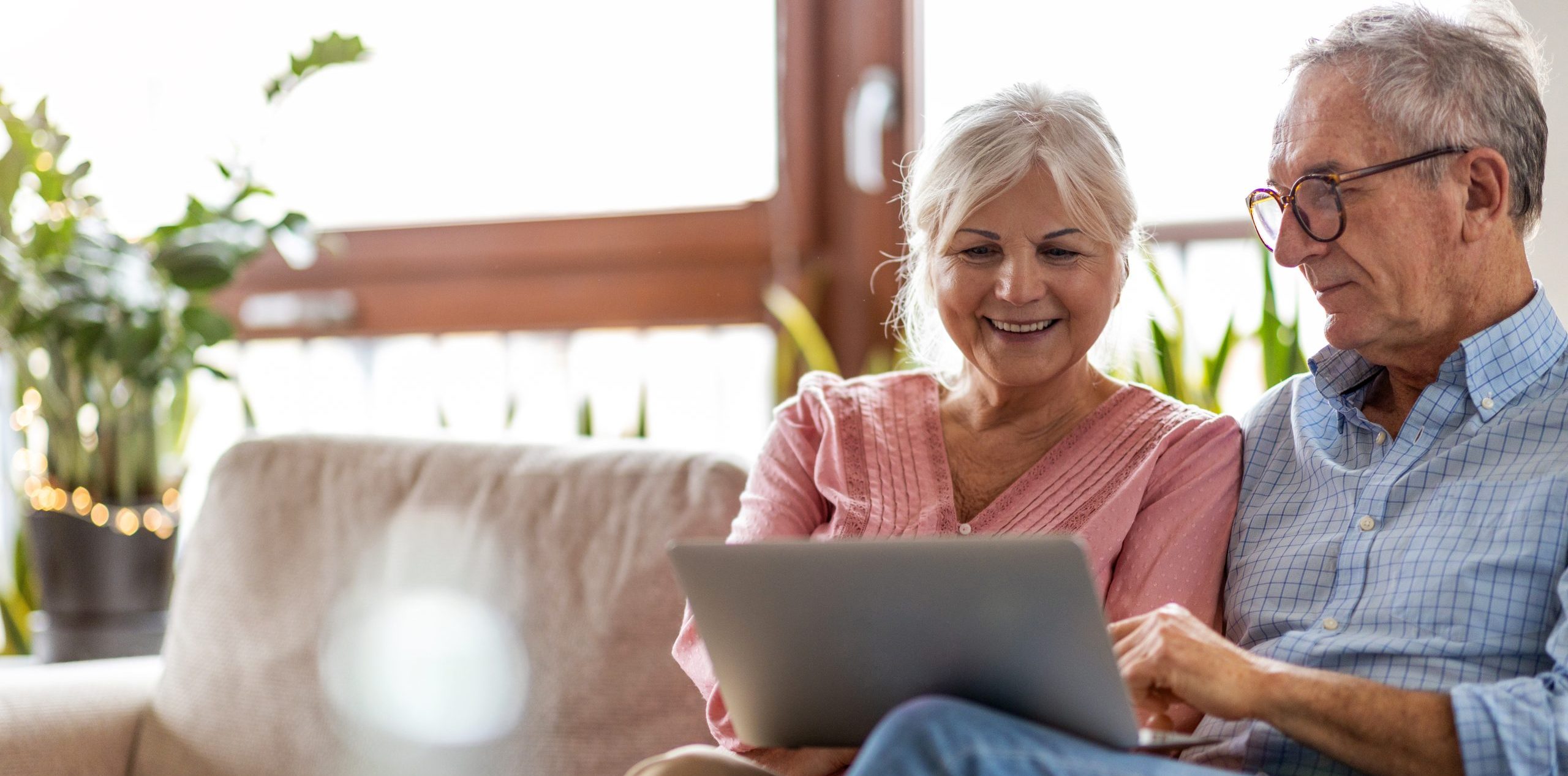 elderly couple on a couch and using an ipad