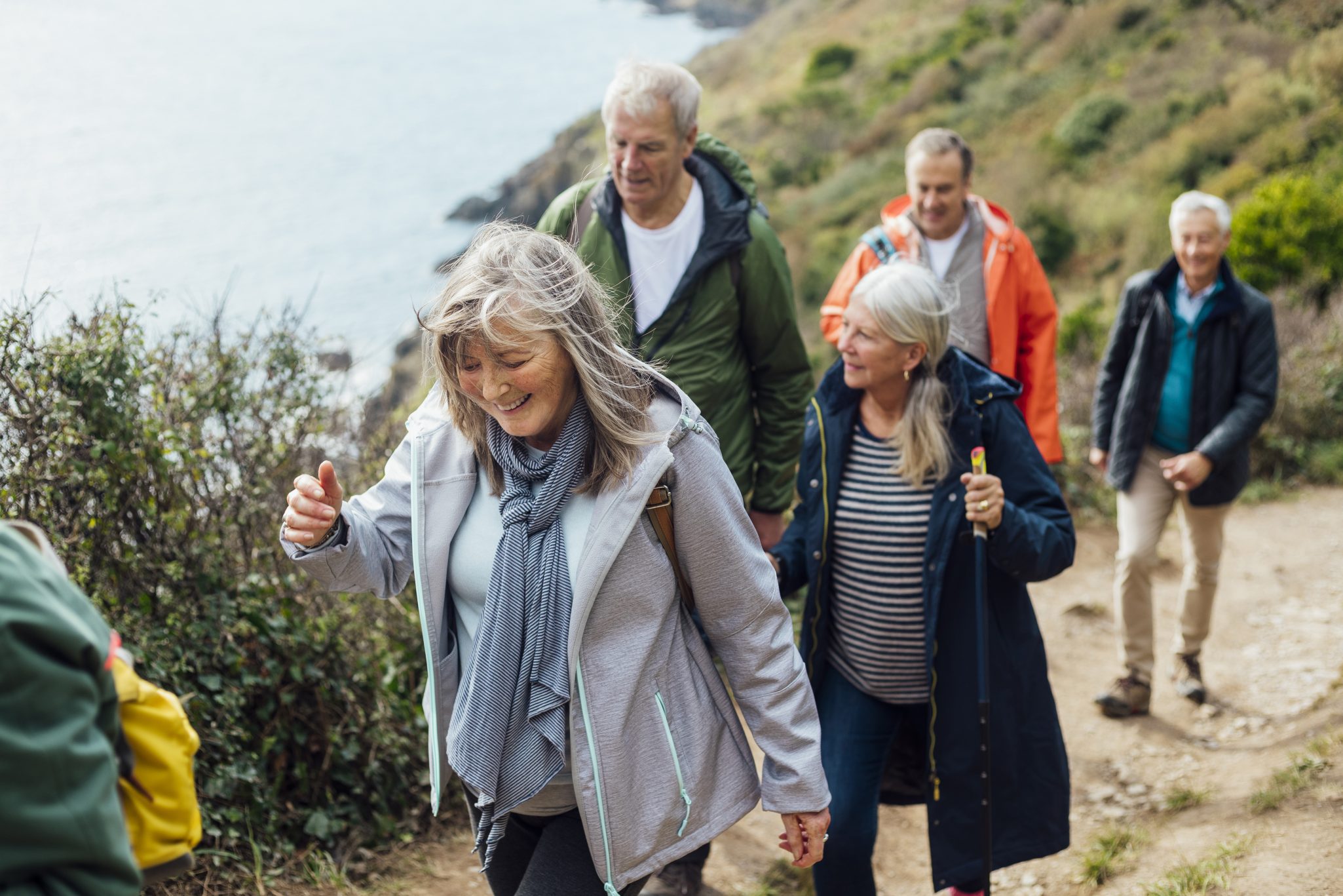 A group of elderly individuals walking on a scenic trail enjoying nature and engaging in physical activity 