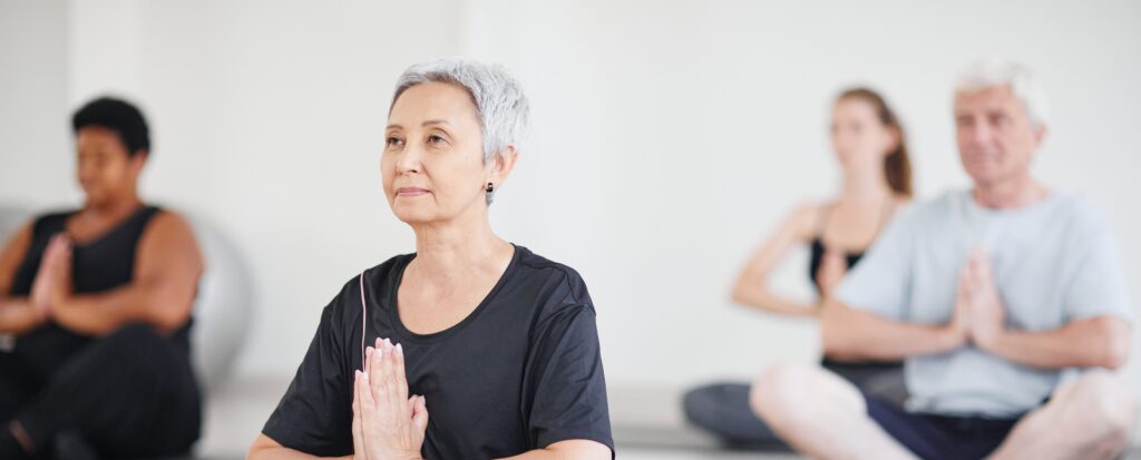 four elderly people seated doing yoga