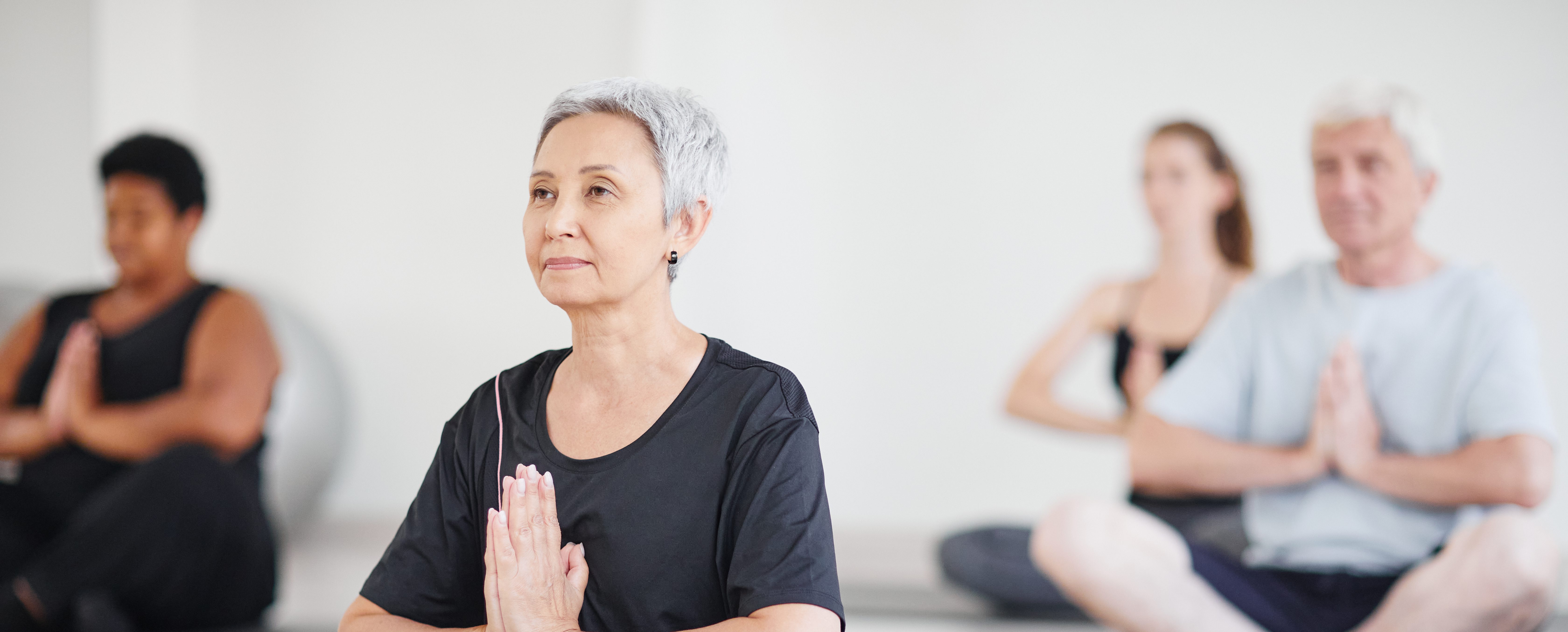 four elderly people seated doing yoga