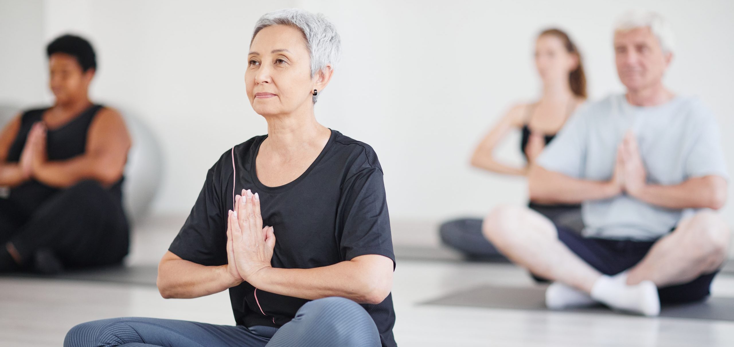 four elderly people seated doing yoga