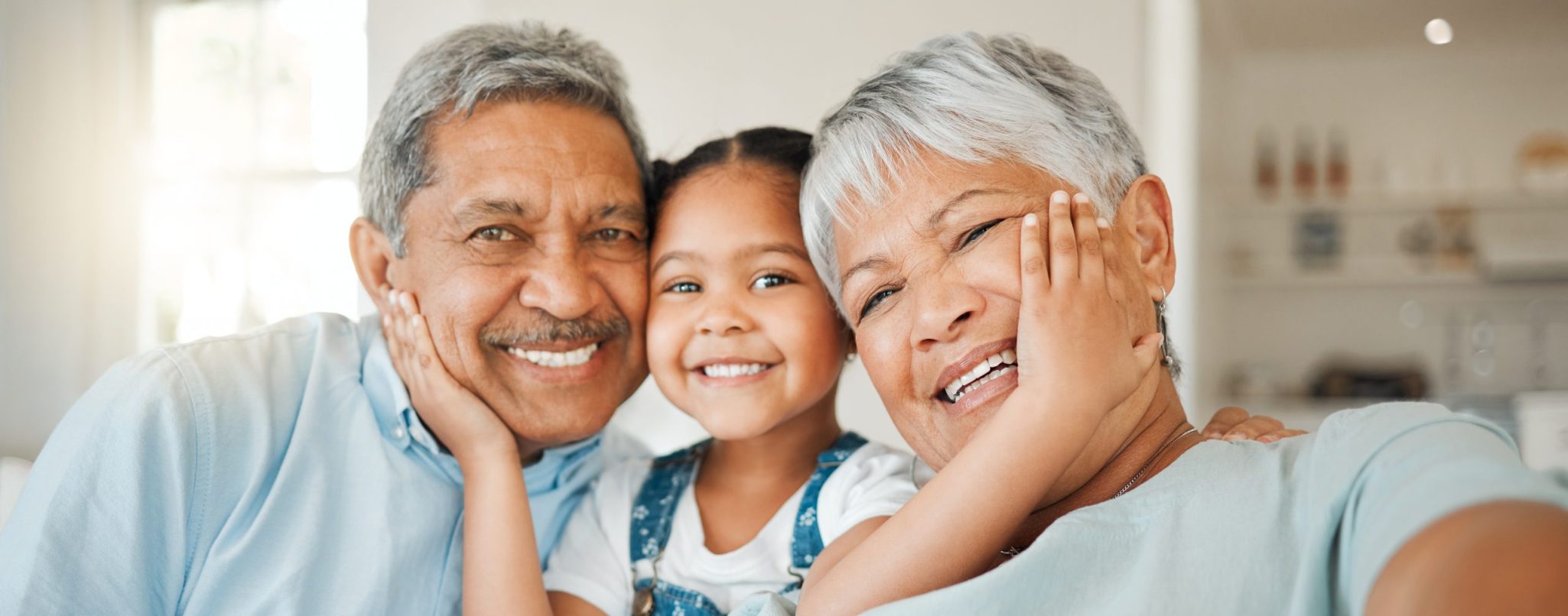 Shot of grandparents bonding with their granddaughter on a sofa at home An older couple and their child smiling happily, radiating warmth and love in a heartwarming family moment.