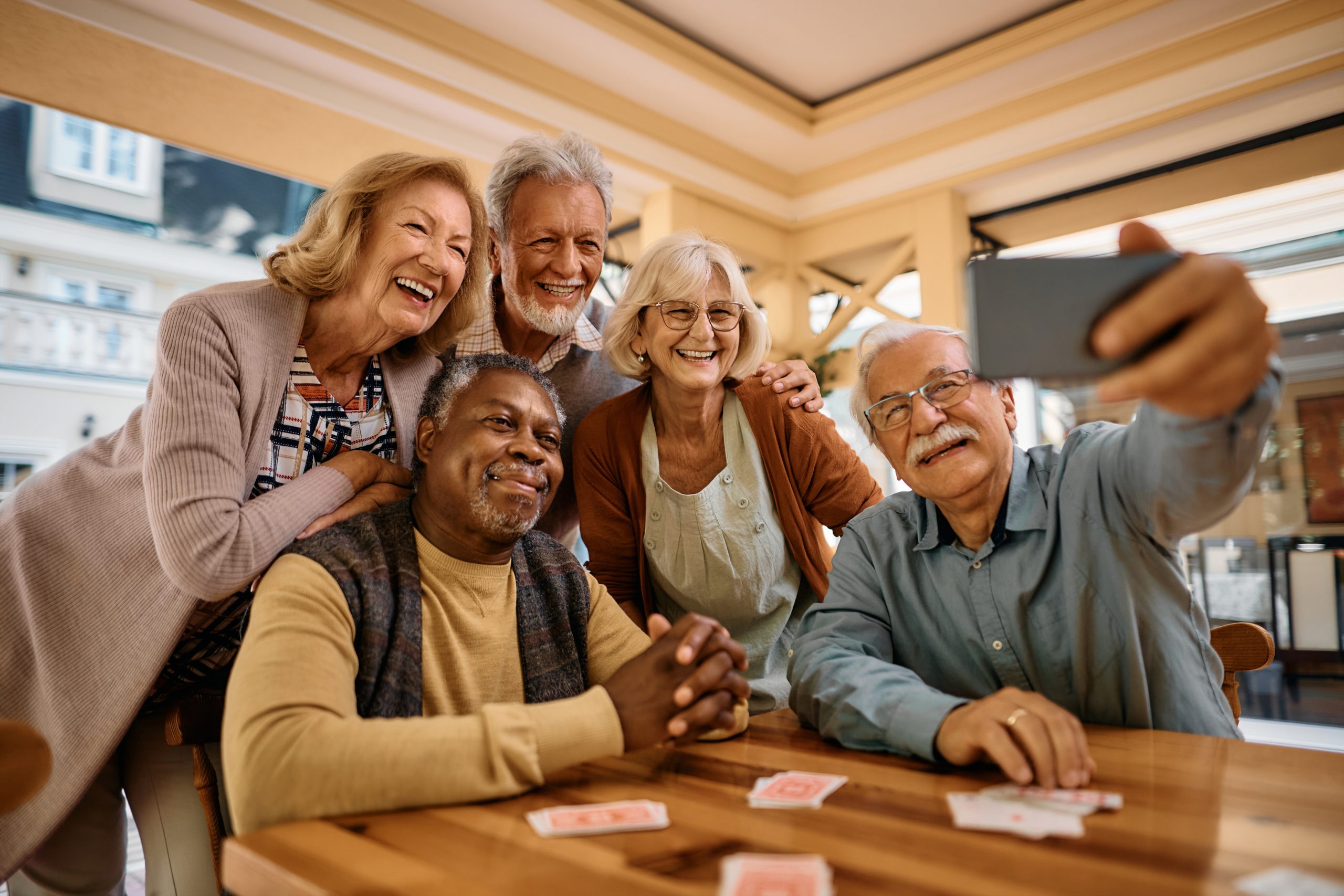 Elderly individuals enjoying a game of cards in the comfort of their community taking a selfie