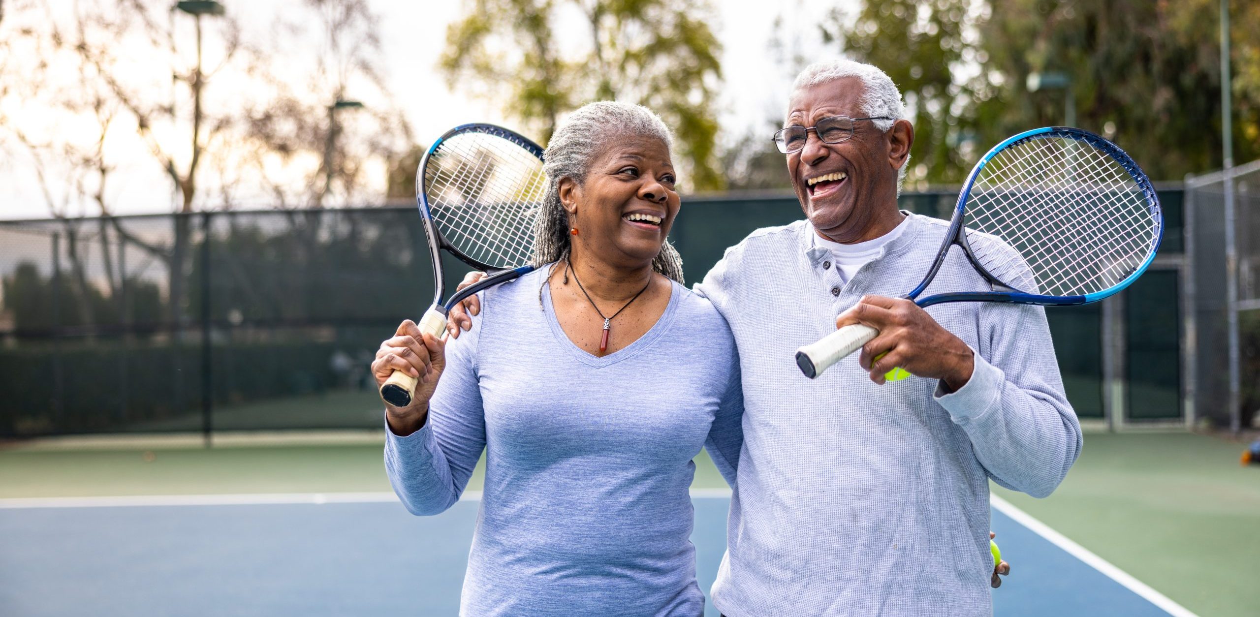 two elderly people with tennis rackets on a tennis court