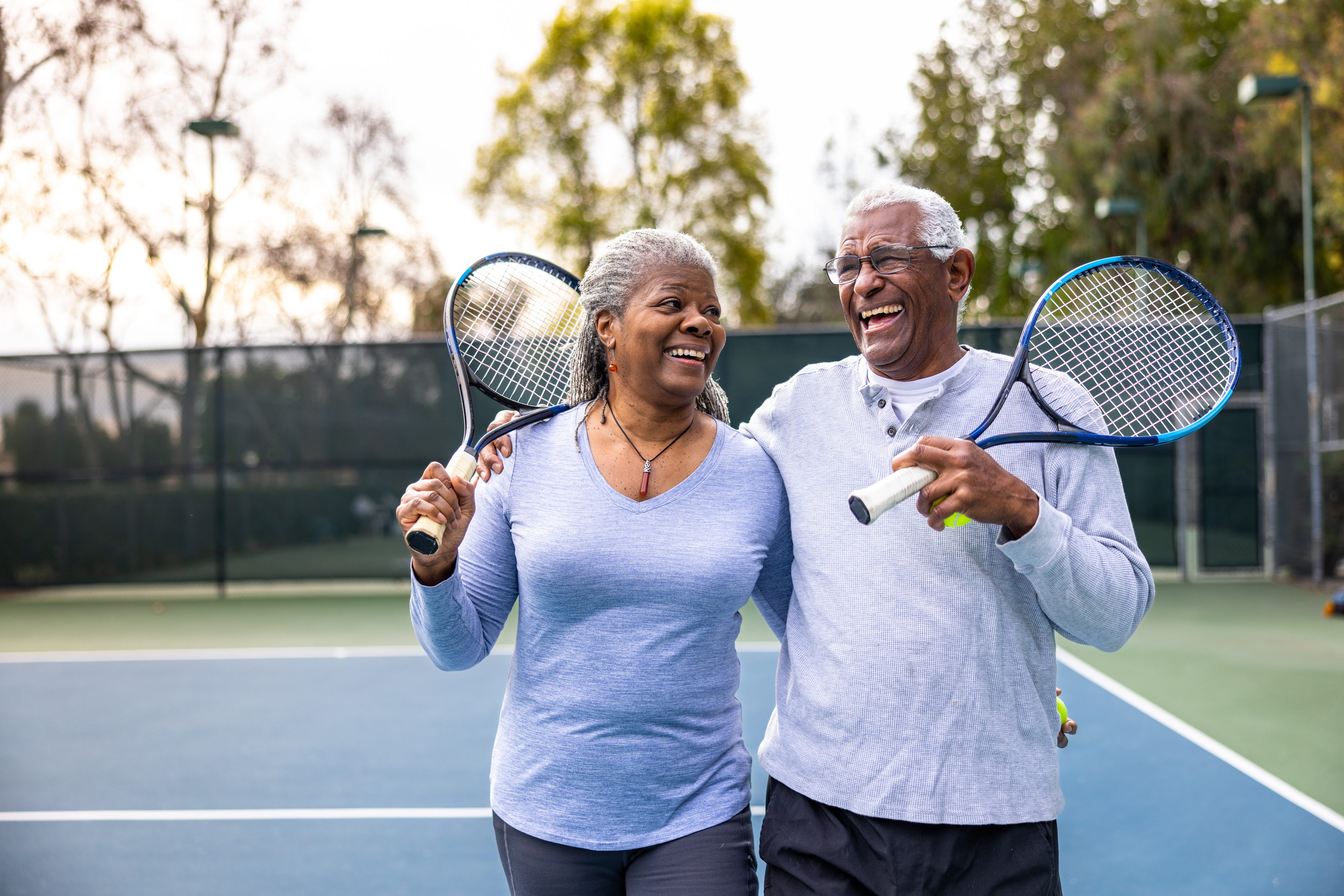two elderly people with tennis rackets on a tennis court