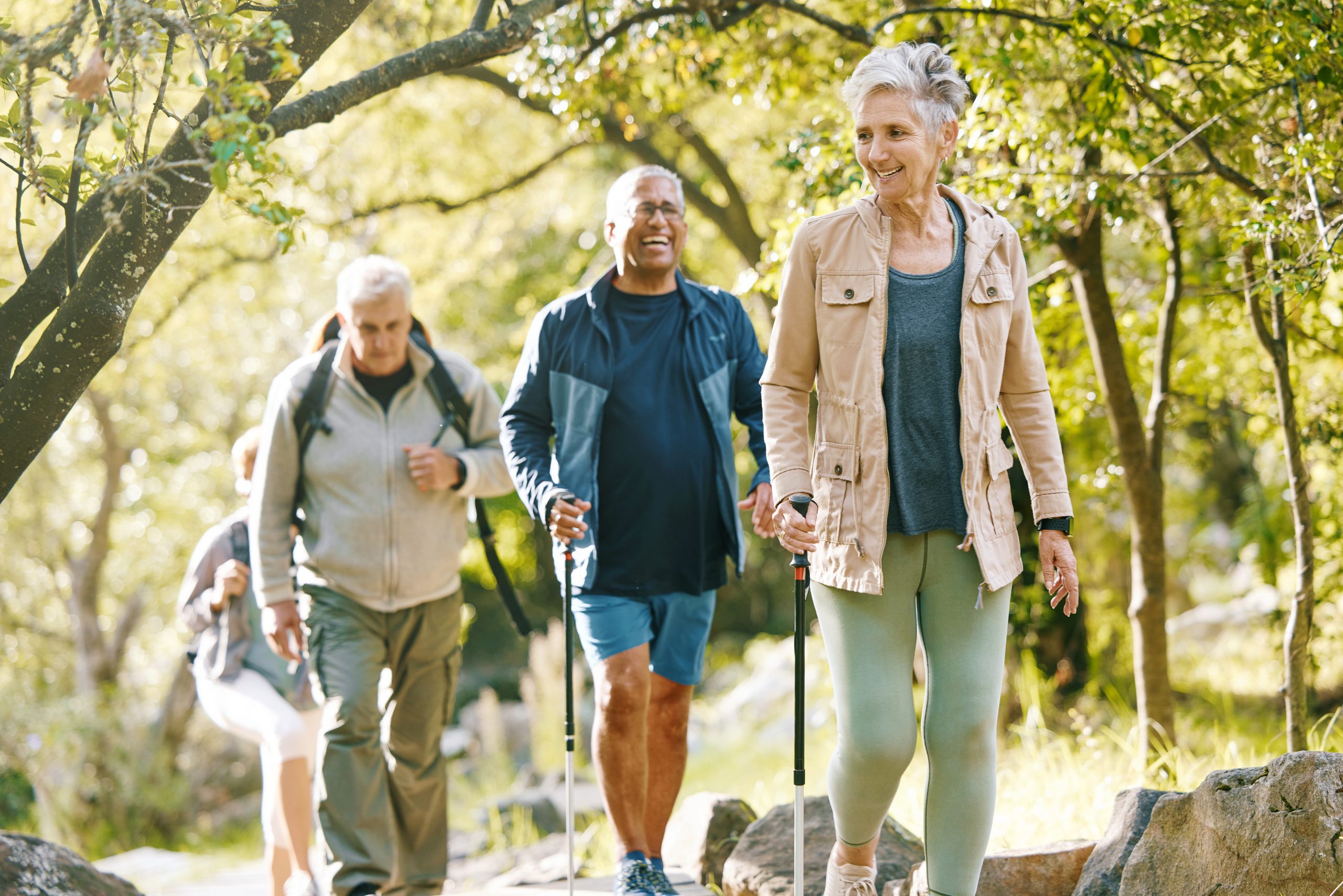 3 elderly people hiking through the woods with walking sticks