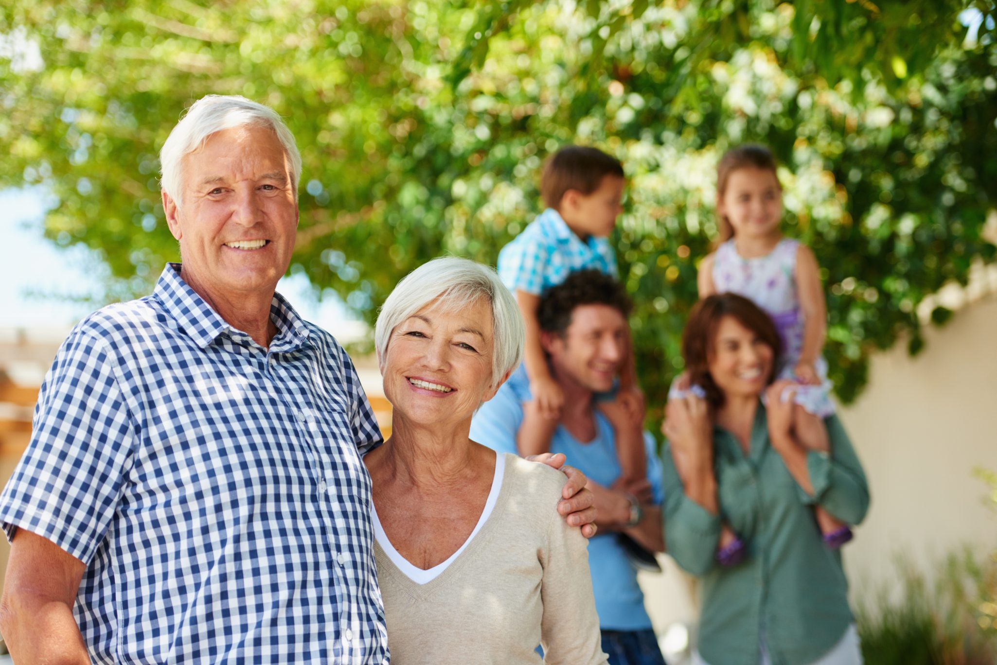 two grandparents smiling with their kids and grandkids behind them