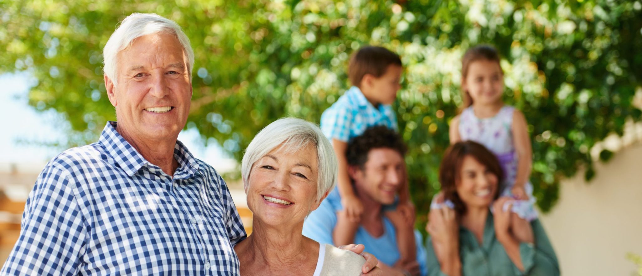 two grandparents smiling with their kids and grandkids behind them