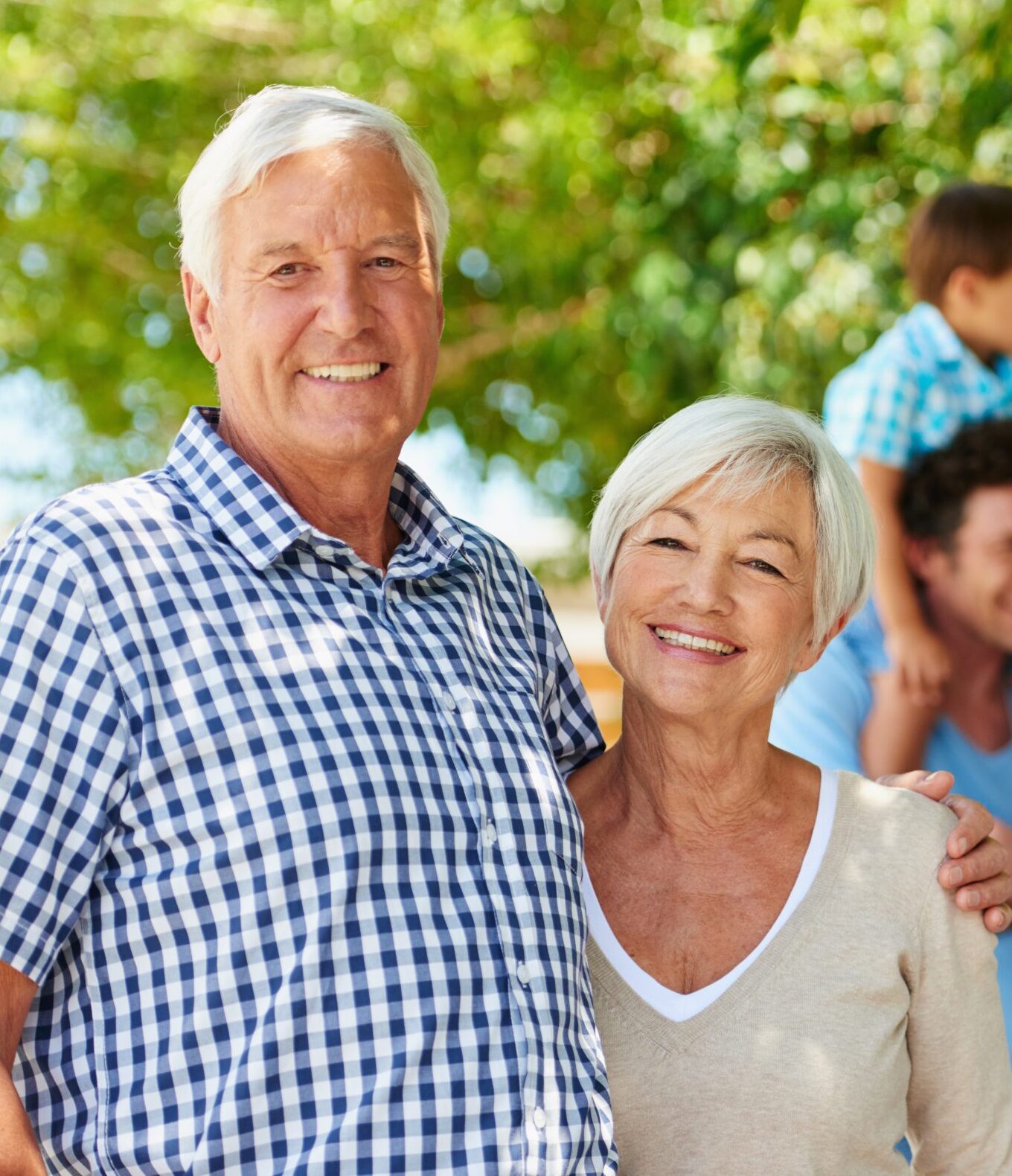 two grandparents smiling with their kids and grandkids behind them