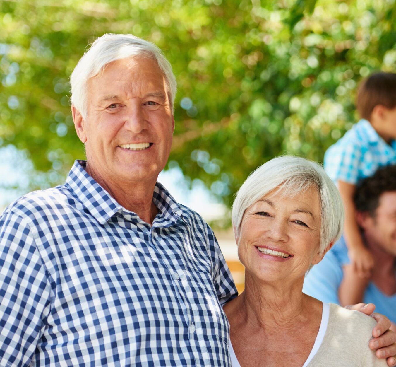 two grandparents smiling with their kids and grandkids behind them