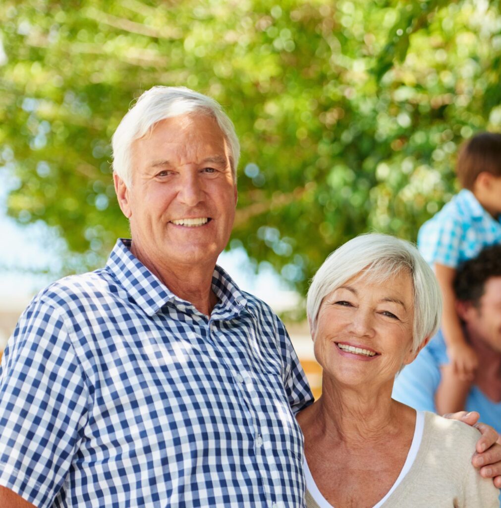 couple smiling with adult children and grandchildren in background