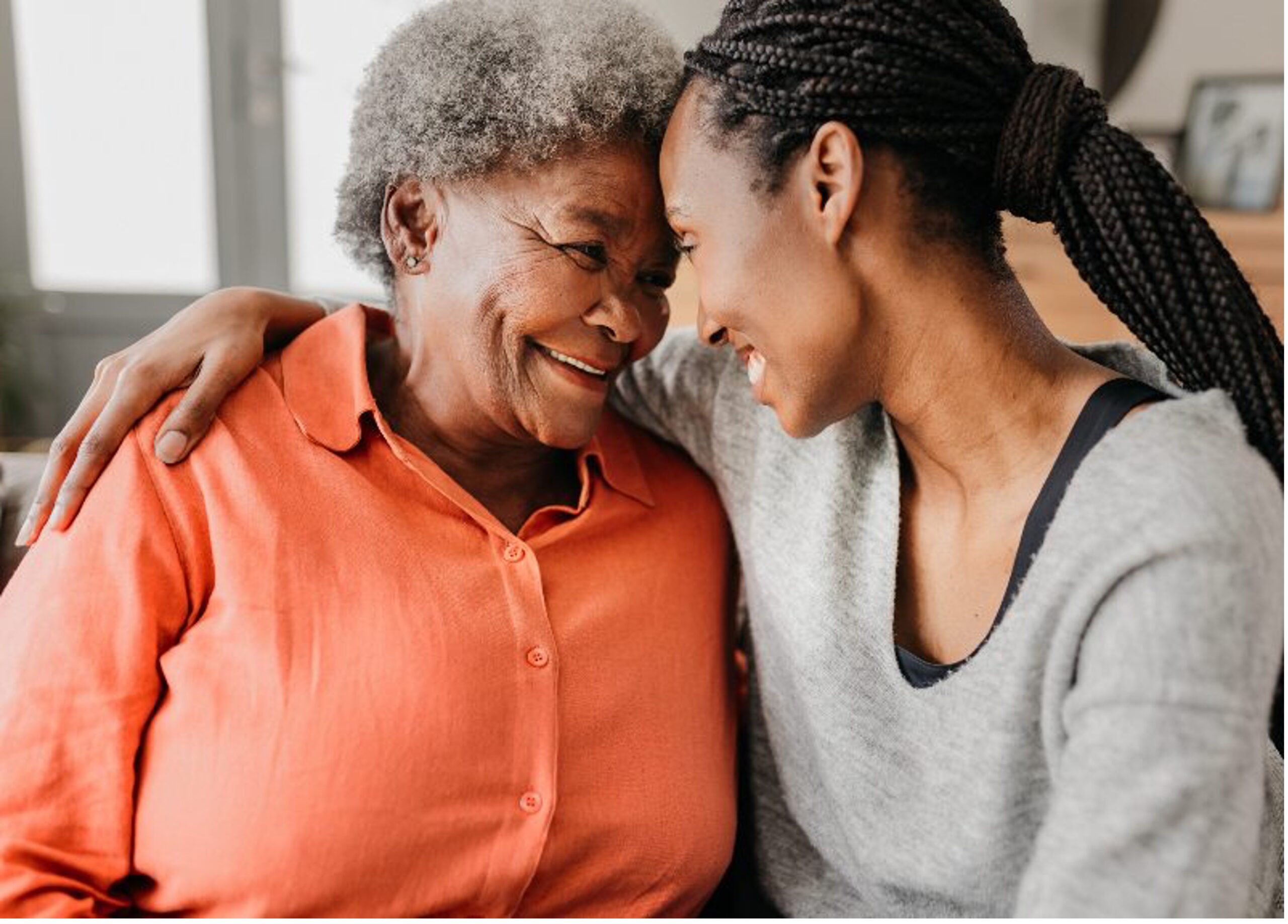 A woman and her daughter with their foreheads together and smiling by Senior Resource Group