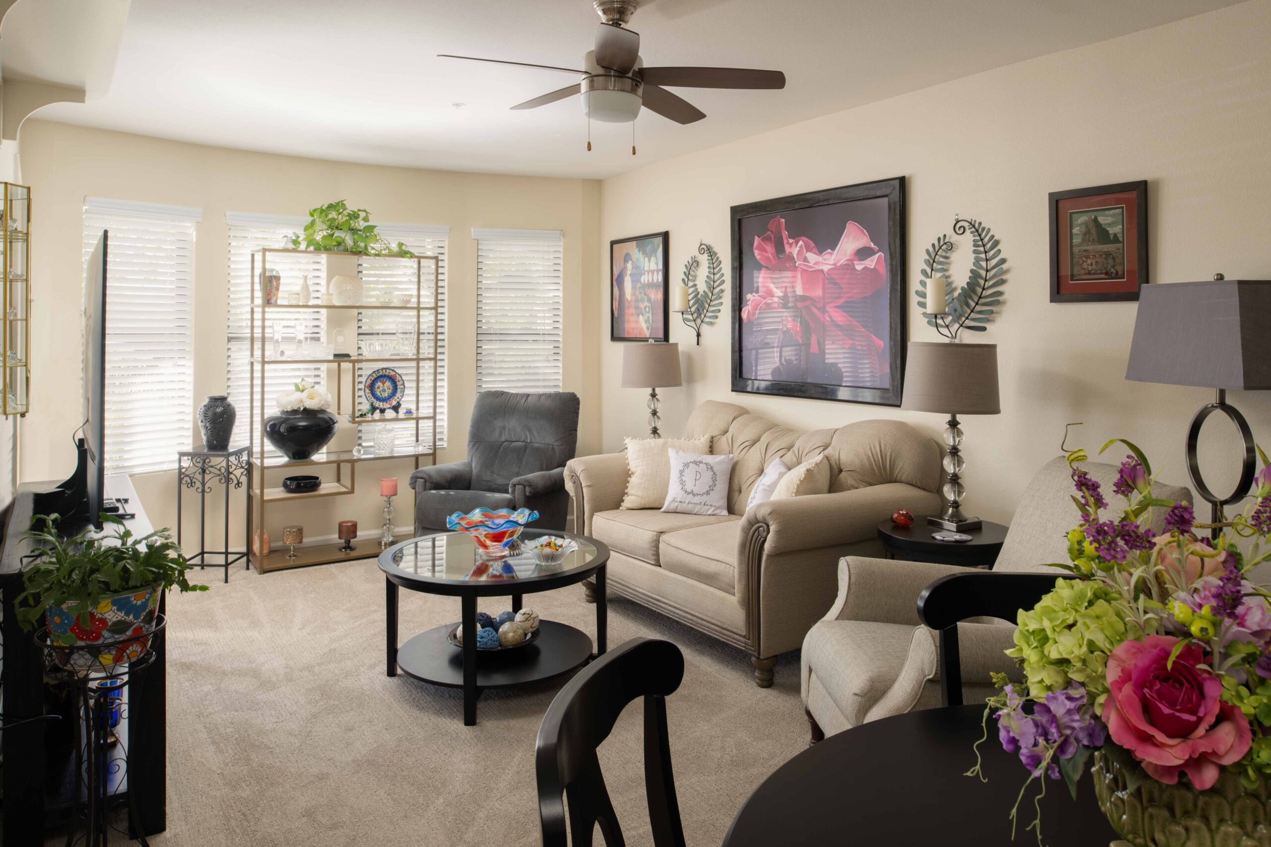 Model living room with a cream sofa and ceiling fan.