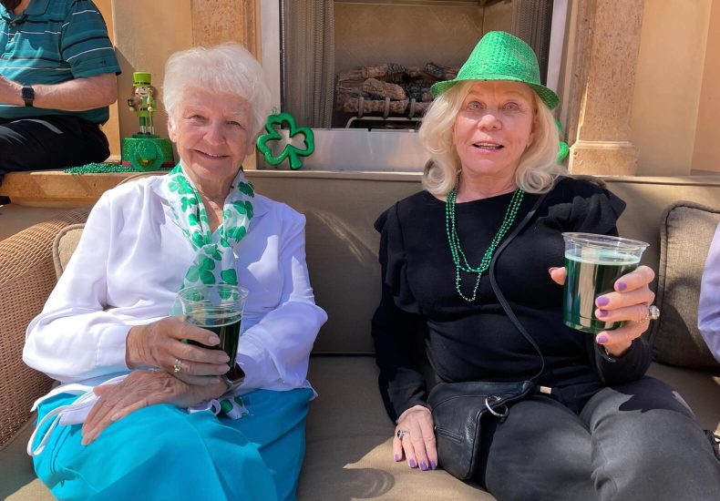 Three elderly women enjoying green drinks while sitting on a couch.