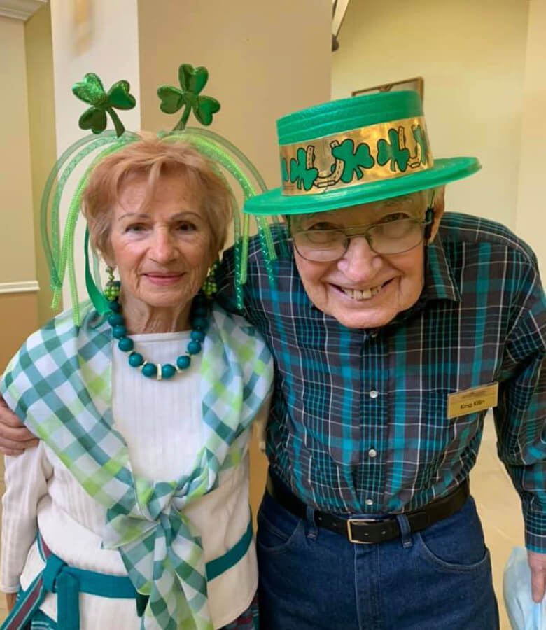 An elderly couple wearing matching green hats and clothes, enjoying a day together.