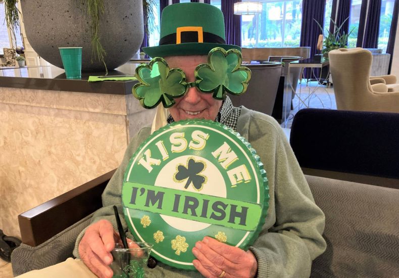 An elderly man with green glasses and a shamrock hat, adding a touch of charm and festivity to his appearance.