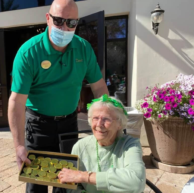 A man in a green shirt holding a tray of green coins.